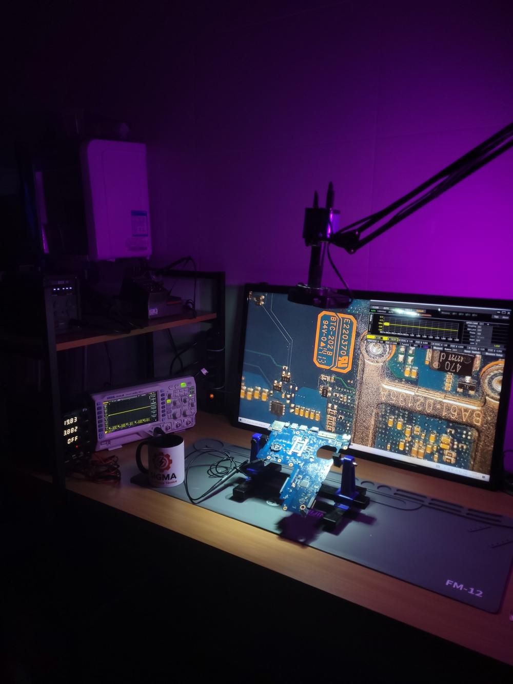Placa-mãe de notebook no suporte sob o microscópio, com osciloscópio na bancada da Sigma