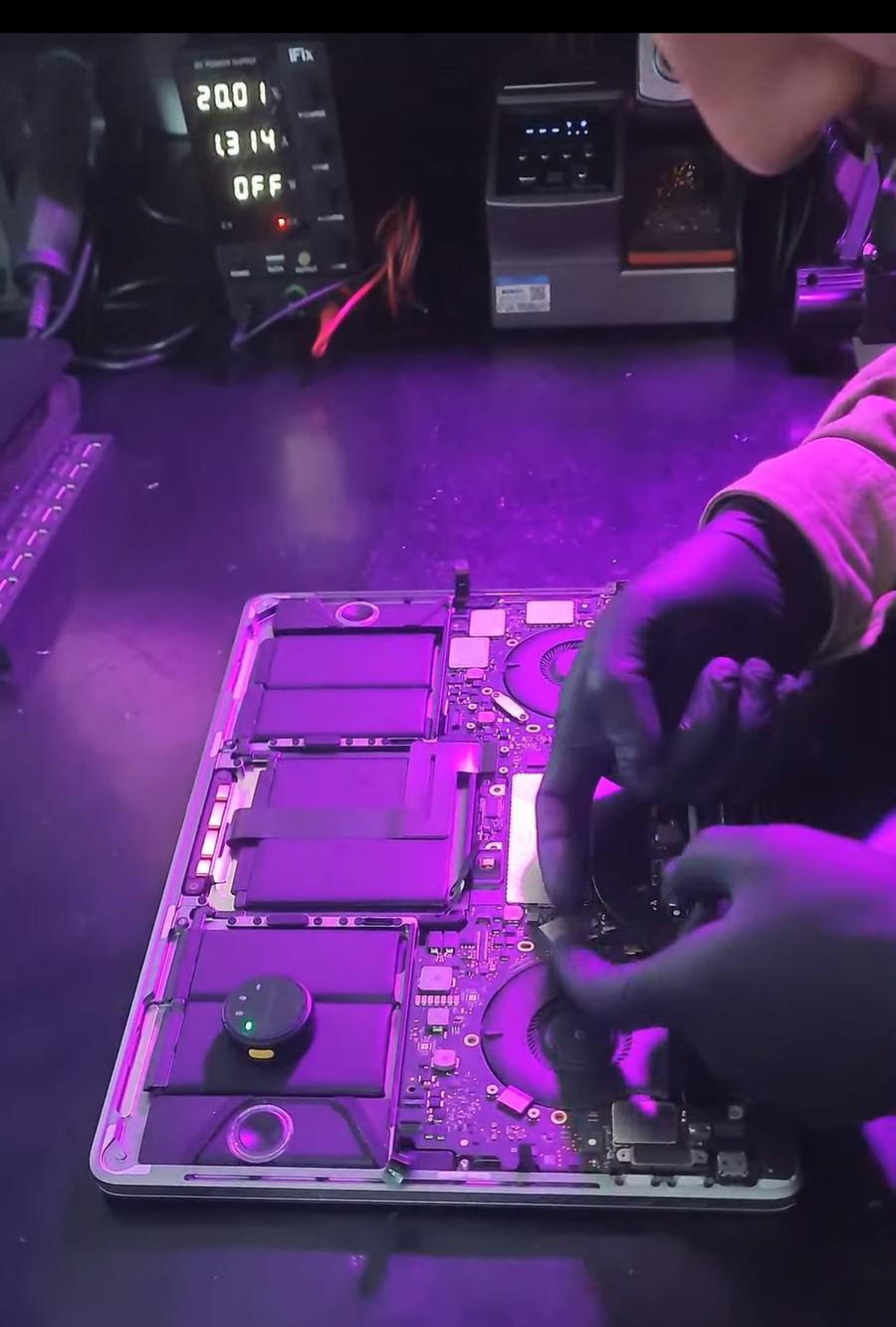 MacBook Pro aberto sendo reparado com fonte de bancada